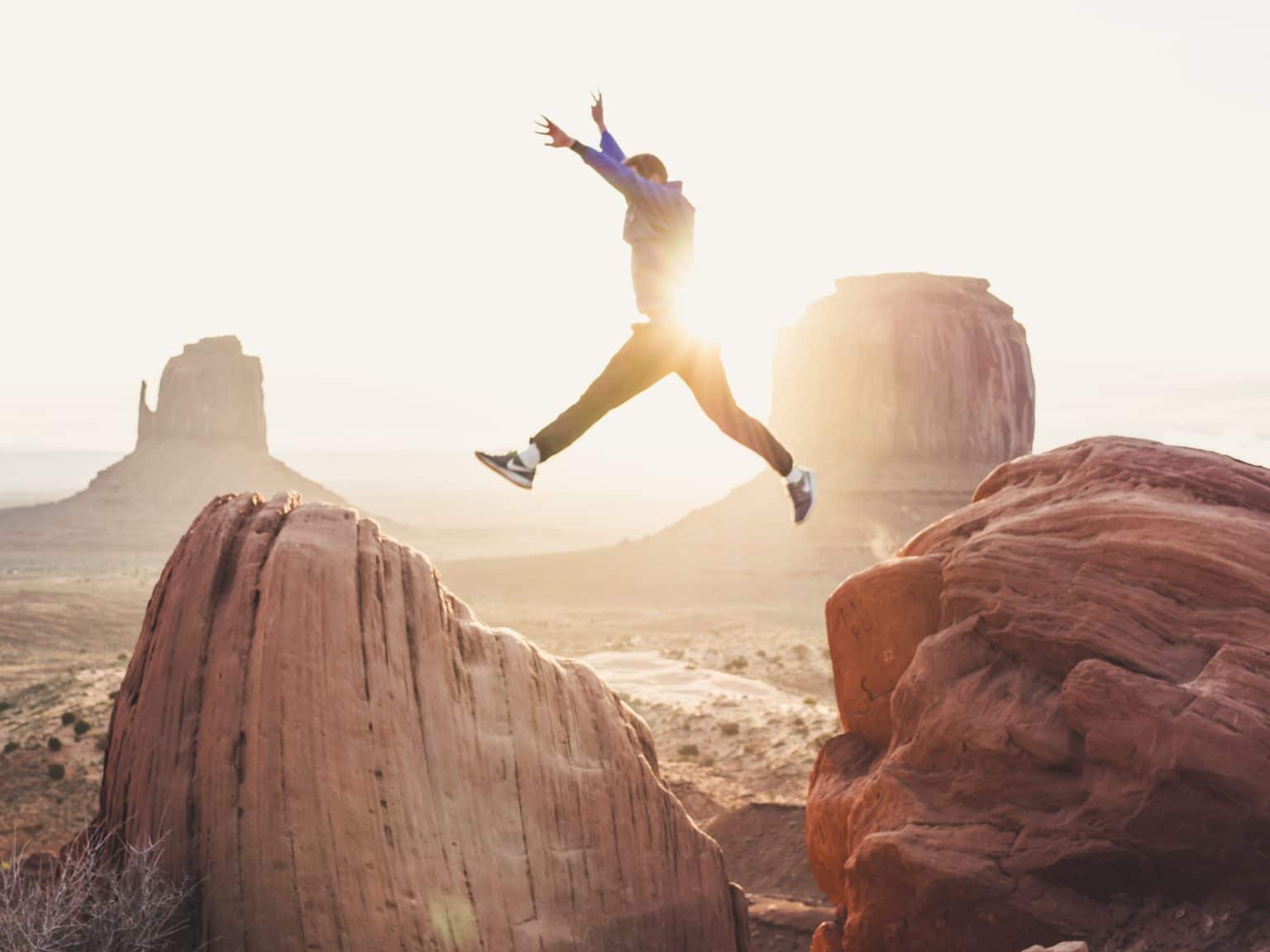 Mann springt über Felsen vor Sonne Grand Canyon