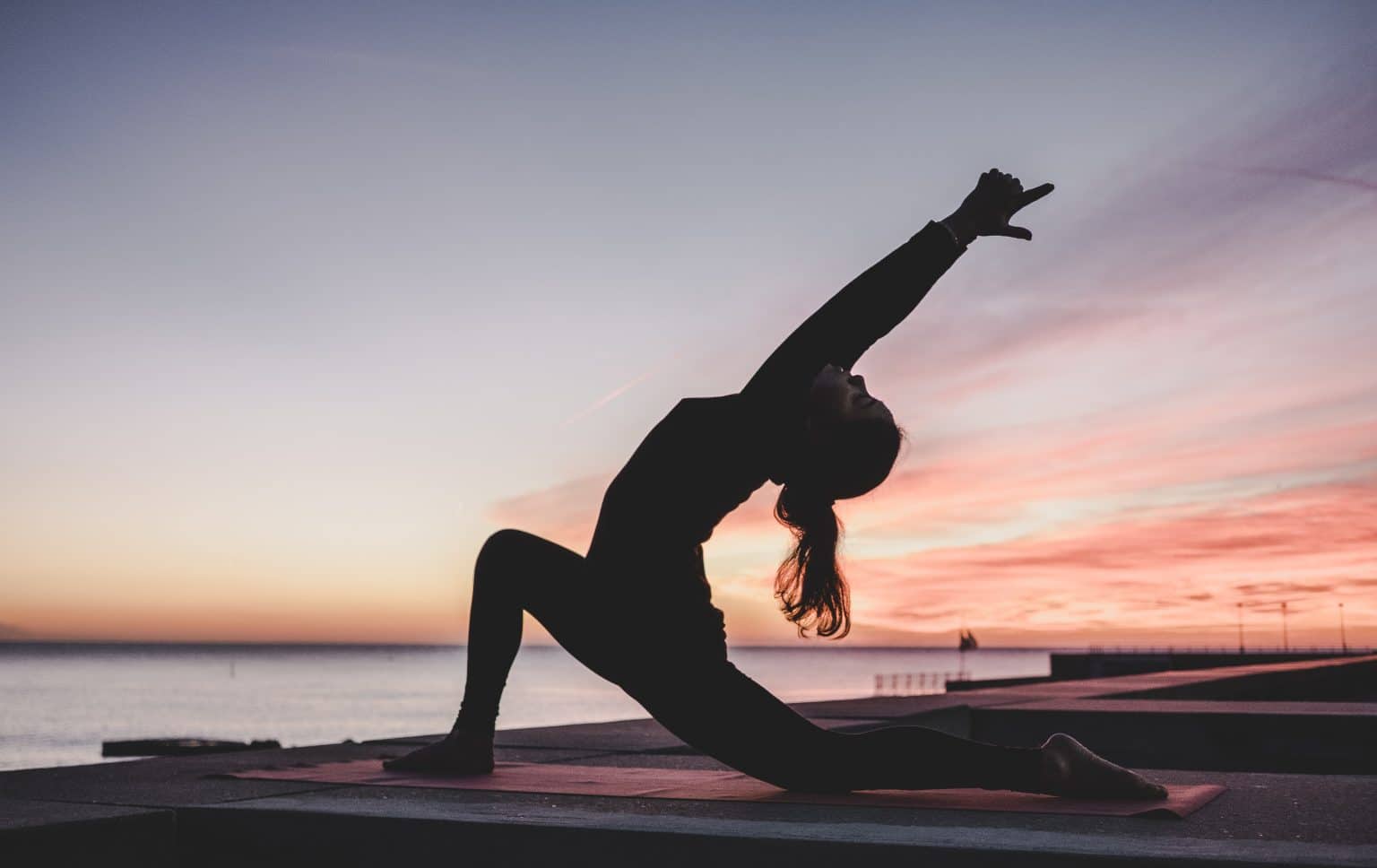 Frau Yogapose silhouette am Wasser vor Sonnenuntergang