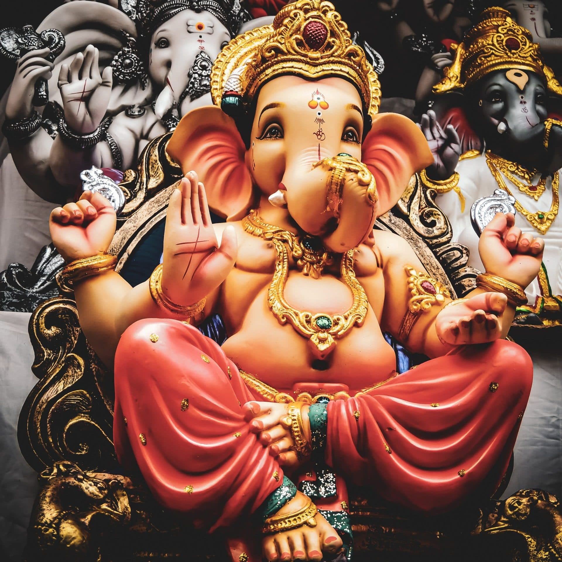 Ganesha Statue Elefantengott orange rot mit Goldschmuck vor anderen Elefantengott Statuen