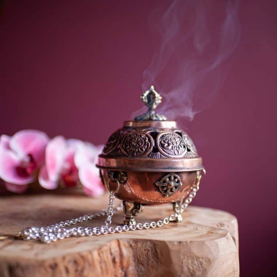 Buddhismus Symbol Dharma Glückssymbole auf Weihrauchbehälter aus Kupfer auf Holz mit Blumen vor roter Wand