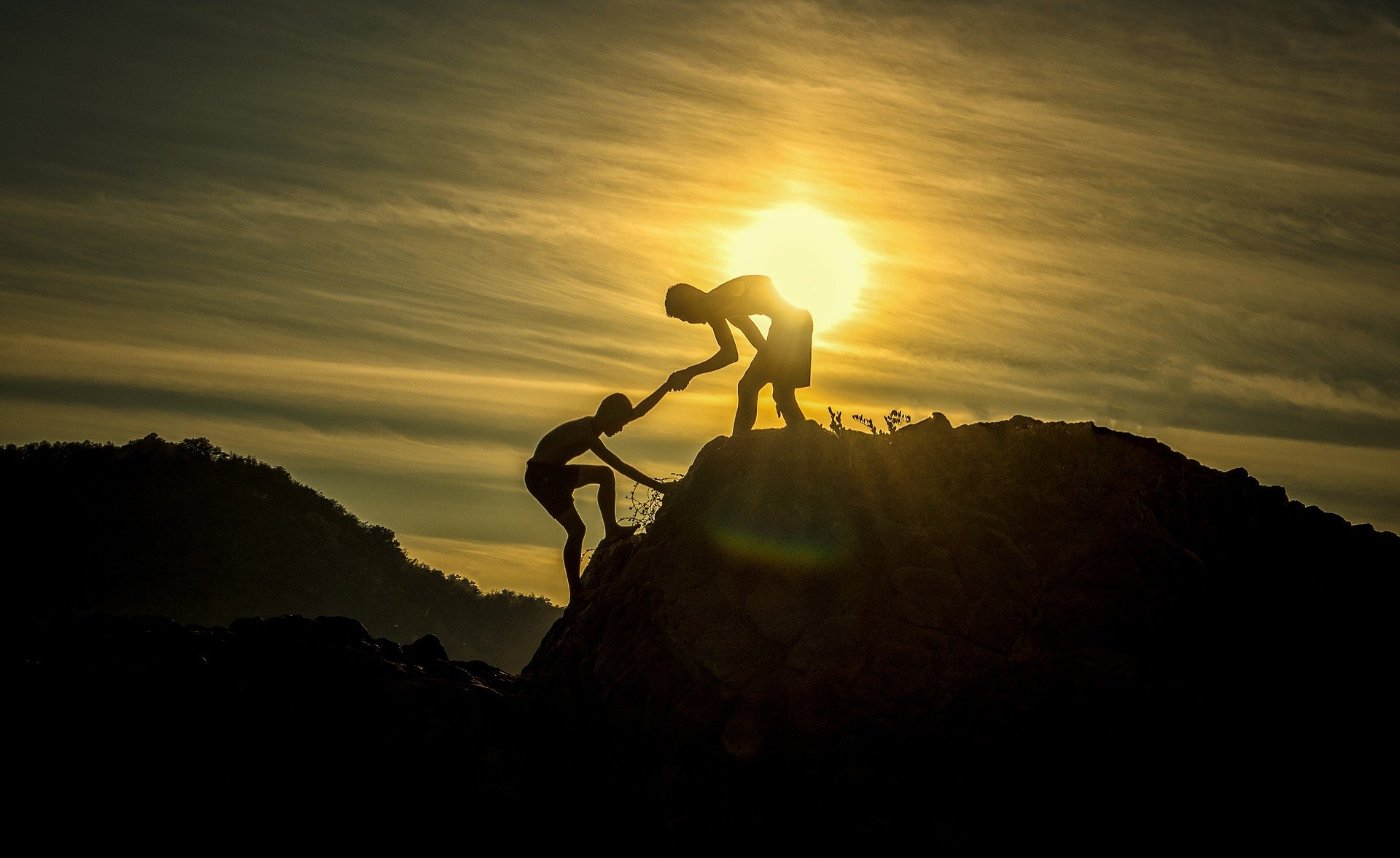 zwei Jungs helfen einander auf einen Berg Silhouette vor sonnenaufgang