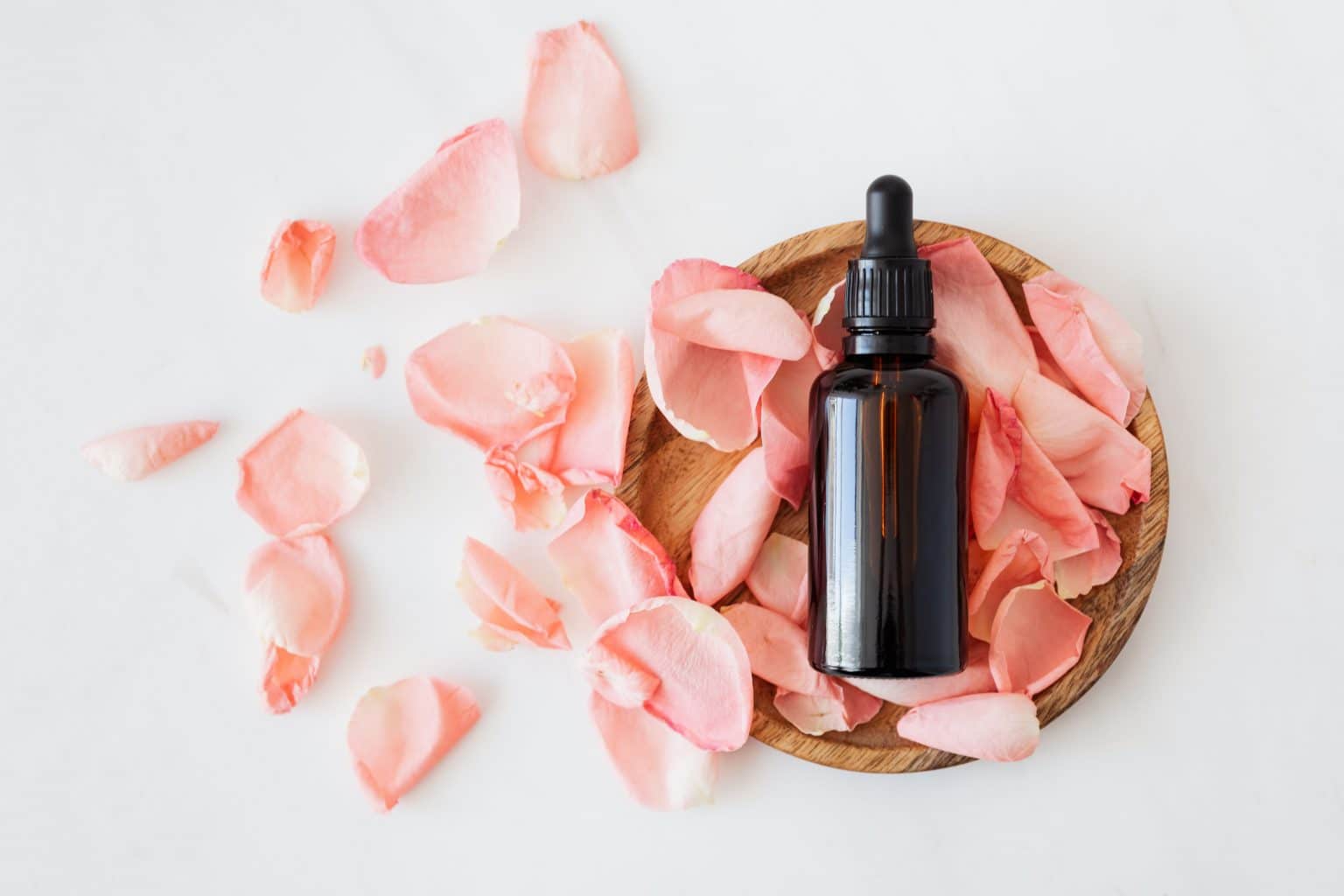 Massageöl pipetten flasche mit rosenblüten auf Holzteller