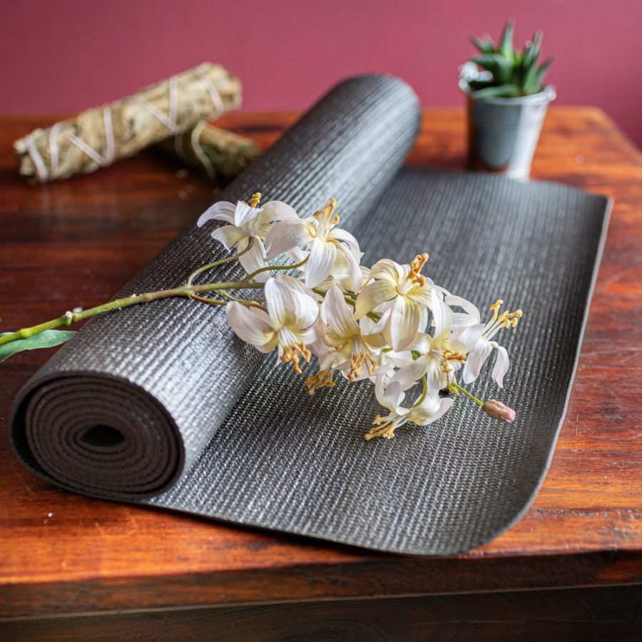 schwarze Yogamatte mit Blumen auf Holz